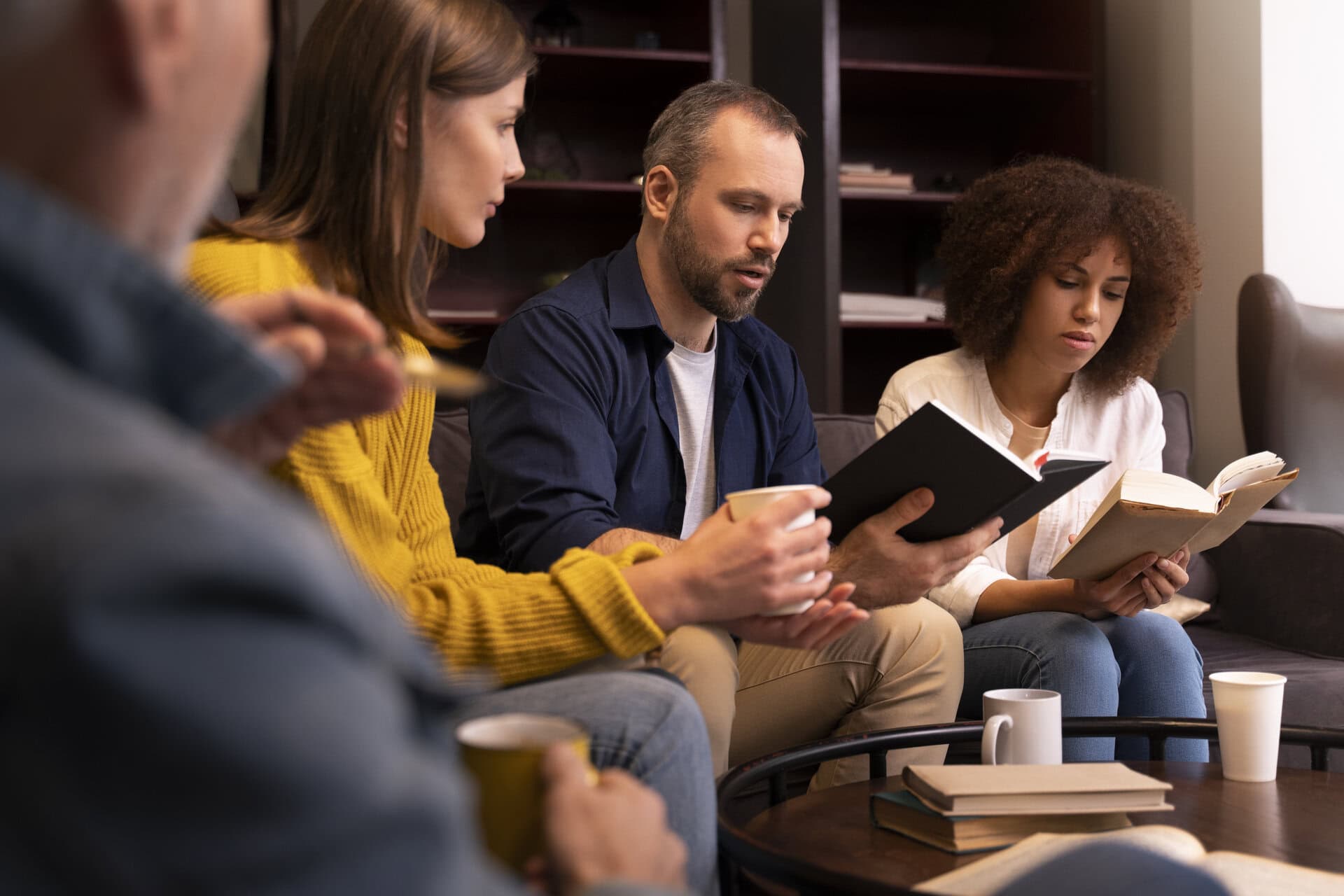People relaxing in a cosy lounge space, reading and discussing books by the School of Evangelism as part of their personal journey and exploration of faith.